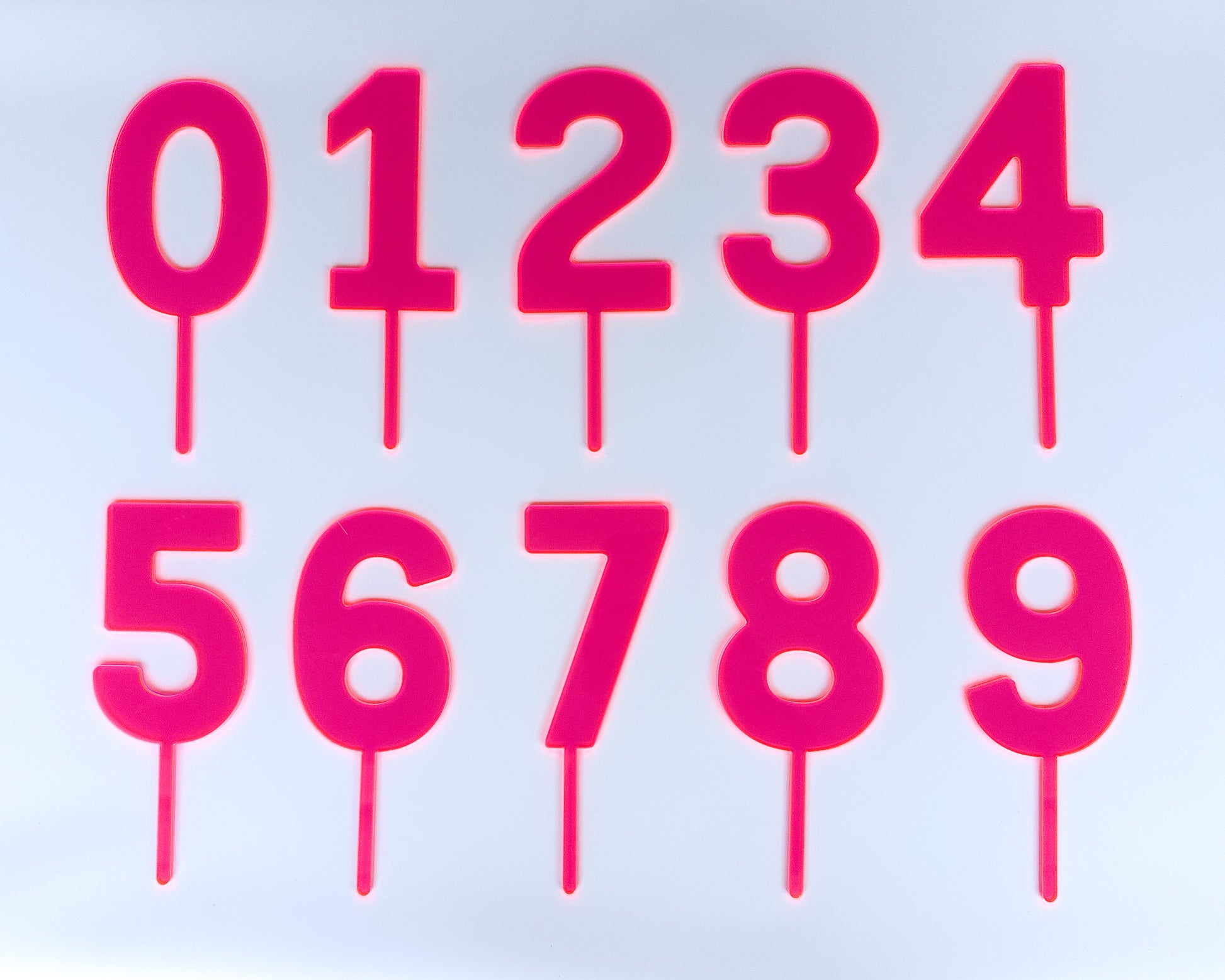 Pink number cake toppers 0 through 9 on a light blue background