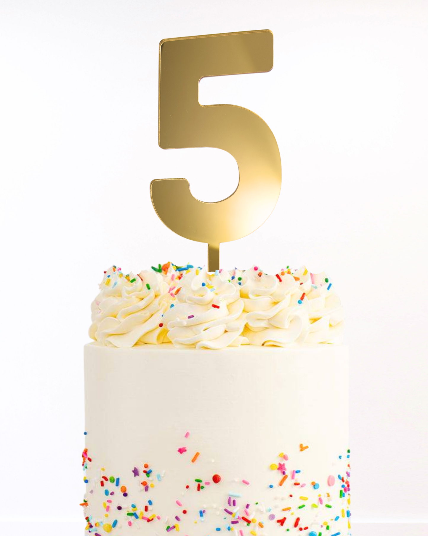 White cake with a gold number cake topper on a white background