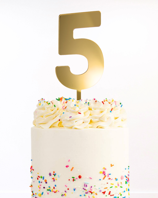 White cake with a gold number cake topper on a white background