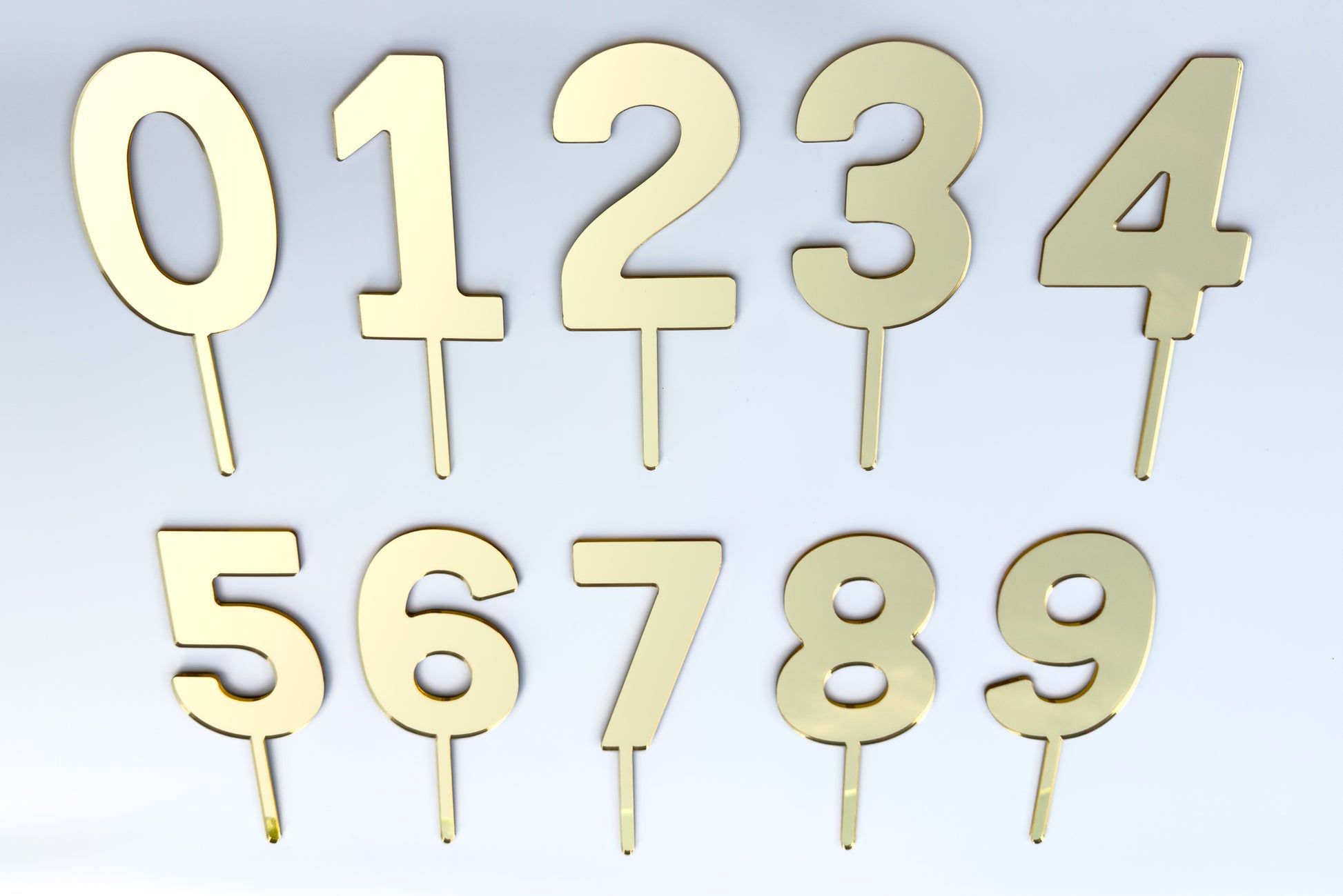 Set of gold metallic number cake toppers on a light gray background
