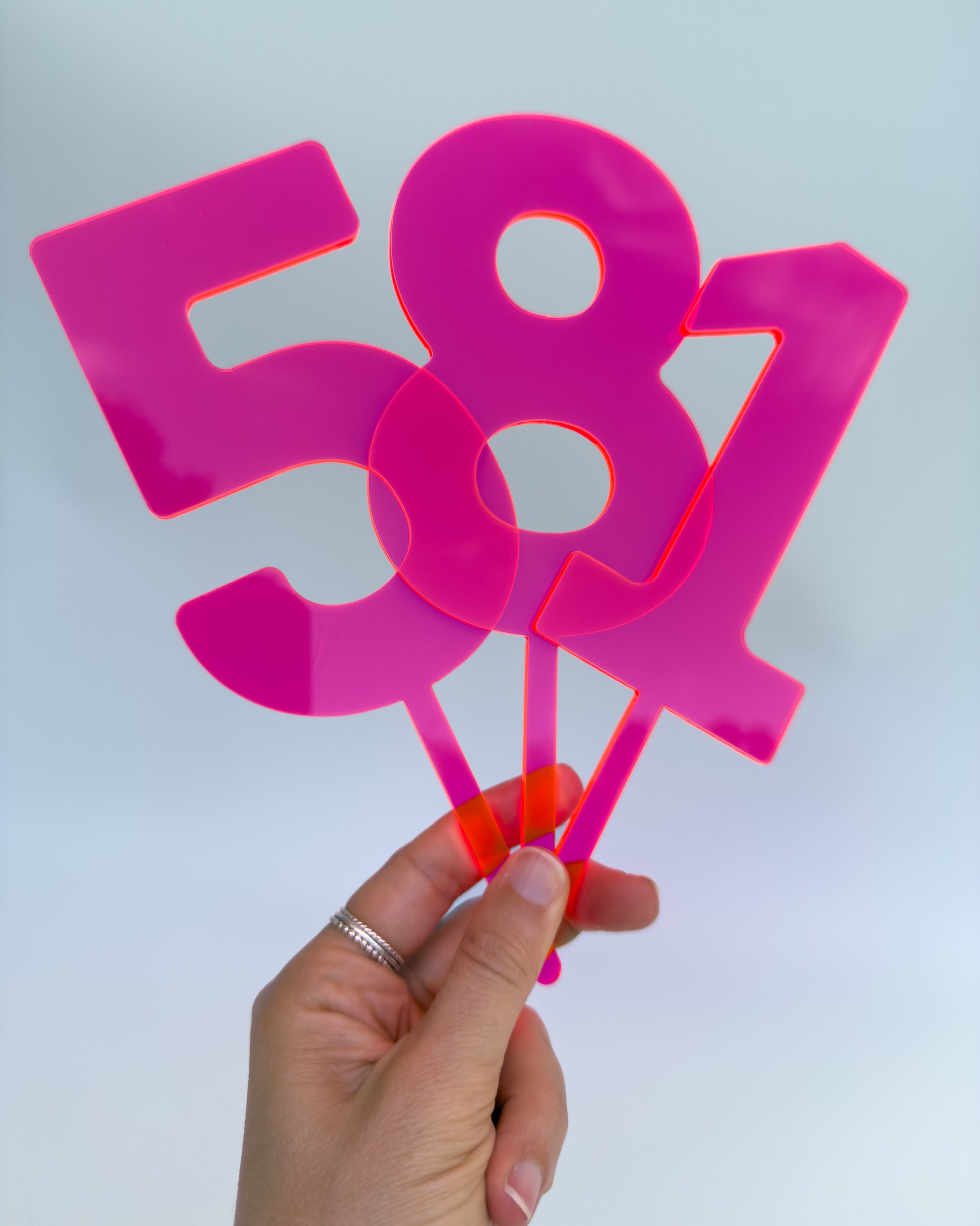 Hand holding pink acrylic number cake toppers